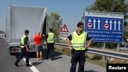 FILE - Austrian police officers control cars arriving to Austria at a checkpoint in the village of Nickelsdorf, Aug. 31, 2015.