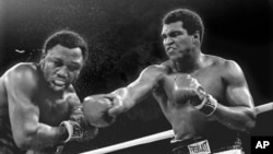 FILE - Spray flies from the head of challenger Joe Frazier as heavyweight champion Muhammad Ali connects with a right in the ninth round of their title fight in Manila, Philippines, Oct. 1, 1974. Ali has died, his family said, June 3, 2016. He was 74. 