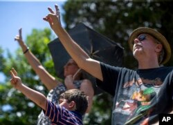 Mourners hold up peace signs during Gregg Allman's burial at Rose Hill Cemetery, June 3, 2017, in Macon, Ga. Family, friends and fans gathered to say goodbye to music legend Gregg Allman, who died Memorial Day weekend at the age of 69.