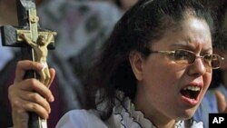 An Egyptian Coptic Christian woman holds a cross as she protests the recent attacks on Christians and churches, in front of the state television building in Cairo, May 9, 2011