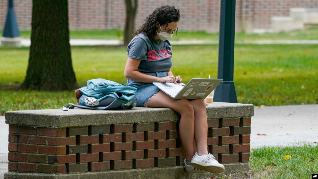 FILE - A masked student works on her laptop on the campus of Ball State University in Muncie, Ind., Sept. 10, 2020. With the spread of Omicron, many colleges are moving classes online for the first few weeks of the new year. (AP File Photo/Michael Conroy)