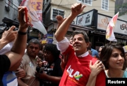 FILE PHOTO: Workers Party presidential candidate Fernando Haddad waves next to his vice presidential candidate Manuela d'Avila at the Rocinha slum in Rio de Janeiro, Brazil Sept. 14, 2018.