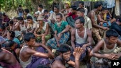 FILE - Rohingya Muslims from Myanmar wait to carry food items from Bangladesh's border toward a no man's land where they set up refugee camps in Tombru, Bangladesh, Sept. 15, 2017. 