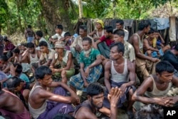 FILE - Rohingya Muslims from Myanmar wait to carry food items from Bangladesh's border toward a no man's land where they set up refugee camps in Tombru, Bangladesh, Sept. 15, 2017.