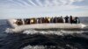 FILE - Migrants, who tried to flee to Europe, travel in a dinghy after they were stopped by Libyan coast guards and made to head to Tripoli, Sept. 29, 2015. 