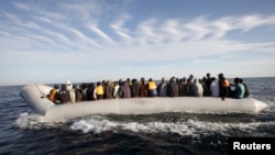 FILE - Migrants, who tried to flee to Europe, travel in a dinghy after they were stopped by Libyan coast guards and made to head to Tripoli, Sept. 29, 2015. 