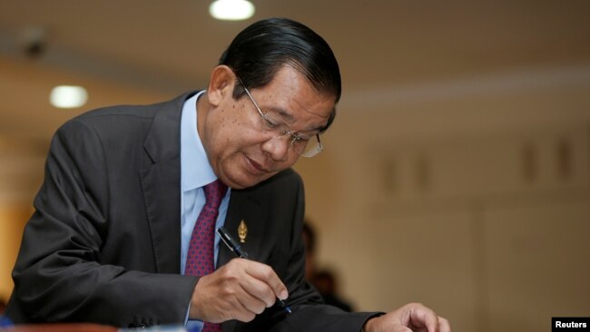 Cambodia's Prime Minister Hun Sen signs a register as he arrives before a plenary session at the National Assembly of Cambodia, in central Phnom Penh, Oct. 12, 2017.