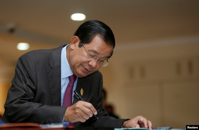 Cambodia's Prime Minister Hun Sen signs a register as he arrives before a plenary session at the National Assembly of Cambodia, in central Phnom Penh, Oct. 12, 2017.