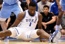 Duke Zion Williamson duduk di lantai setelah sepatunya terbuka selama paruh pertama pertandingan bola basket perguruan tinggi NCAA melawan North Carolina di Durham, N.C., 20 Februari 2019. (Foto: Reuters)