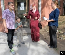 FILE - Syrian refugees Abdullah, left, Fatema, second from right, and their son, Ayham, speak with Liese Klein, development and communications manager for Integrated Refugee & Immigrant Services, outside the agency's office in New Haven, Connecticut, Sept. 2, 2016.