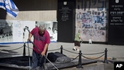 A worker cleans the vandalized memorial site of assassinated Prime Minister Yitzhak Rabin in Tel Aviv, early Friday, Oct. 14, 2011.
