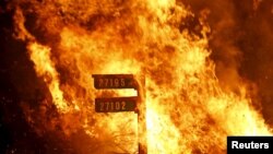 Flames from the Jerusalem Fire consume a sign containing addresses to homes along Morgan Valley Road in Lake County, California, Aug. 12, 2015. 