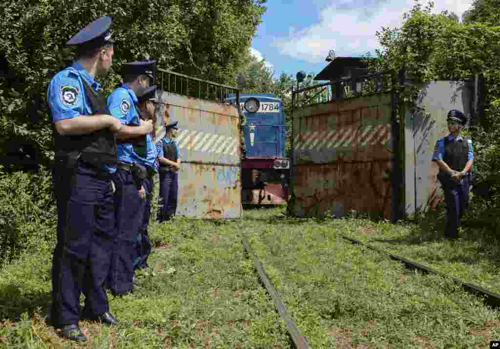 Police officers secure a refrigerated train loaded with bodies of the passengers of Malaysian Airlines flight MH17 as it arrives in a stop in Kharkiv, Ukraine.