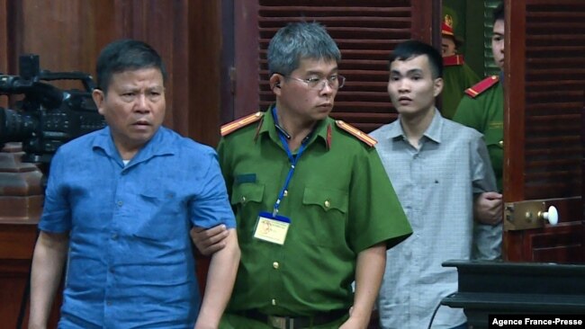 This picture from the Vietnam News Agency taken and released on Nov. 11, 2019 shows Australian citizen Chau Van Kham (L) escorted for trial in Ho Chi Minh City.