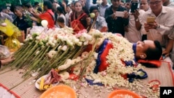 FILE - In this July 11, file photo, the body of Cambodian government critic Kem Ley is covered by the Cambodian National flag as flowers are placed during a funeral ceremony in Phnom Penh, Cambodia. Oeut Ang, the man who allegedly shot dead Kem over what 