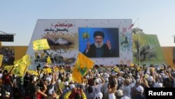 Pendukung Pemimpin Hizbullah di Lebanon, Sayyed Hassan Nasrallah, membawa bendera Hizbullah dan Lebanon, saat mendengarkan pidatonya dalam sebuah perayaan penghentian perang Hizbullah dengan Israel pada 2006. 