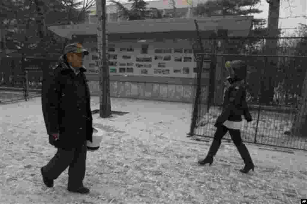 Chinese residents walk past a display board with photographs of North Korea outside the North Korean embassy in Beijing, China, Wednesday, Dec. 12, 2012.