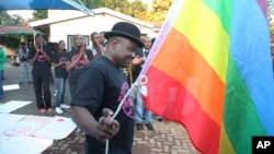 FILE - Chesterfield Samba, director of Gays and Lesbians of Zimbabwe, prepares to hoist the pride flag alongside the Zimbabwean flag during an event in Harare, May, 19, 2012. Zimbabwe's vice president on Feb. 15, 2024, threatened the group for offering university scholarships.