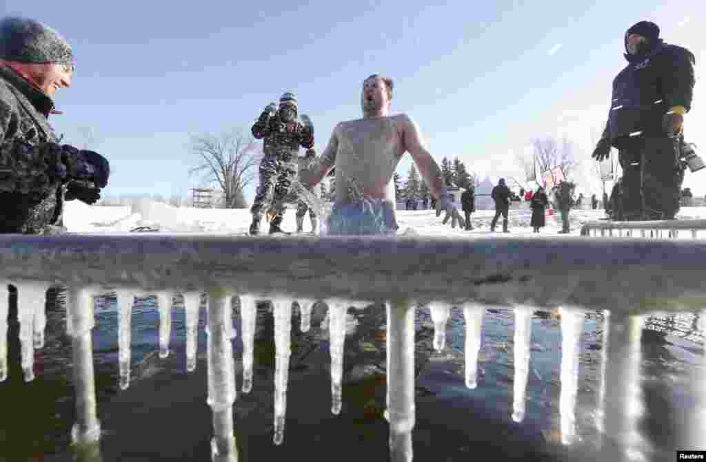 A man jumps into a hole cut in the ice on the Ottawa River during the annual Great Canadian Chill polar bear dip in Ottawa, Jan. 1, 2014.