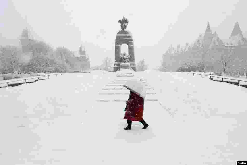 A woman walks past the National War Memorial during heavy snowfall in Ottawa, Canada, February 27, 2013. 