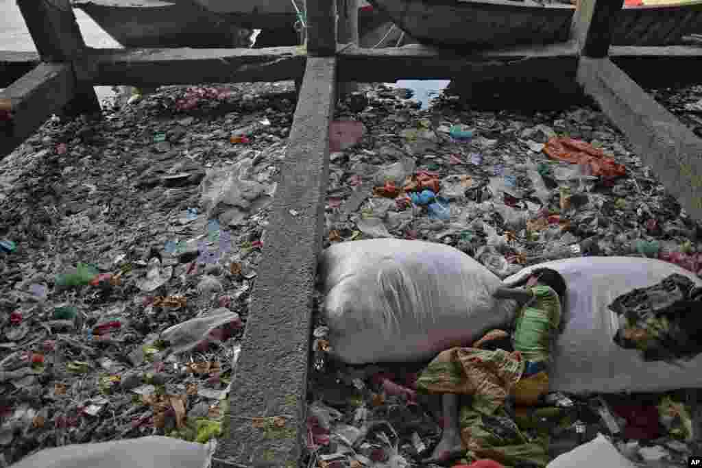A Bangladeshi homeless child sleeps on a garbage bag on the bank of the polluted Buriganga River on World Water Day in Dhaka.
