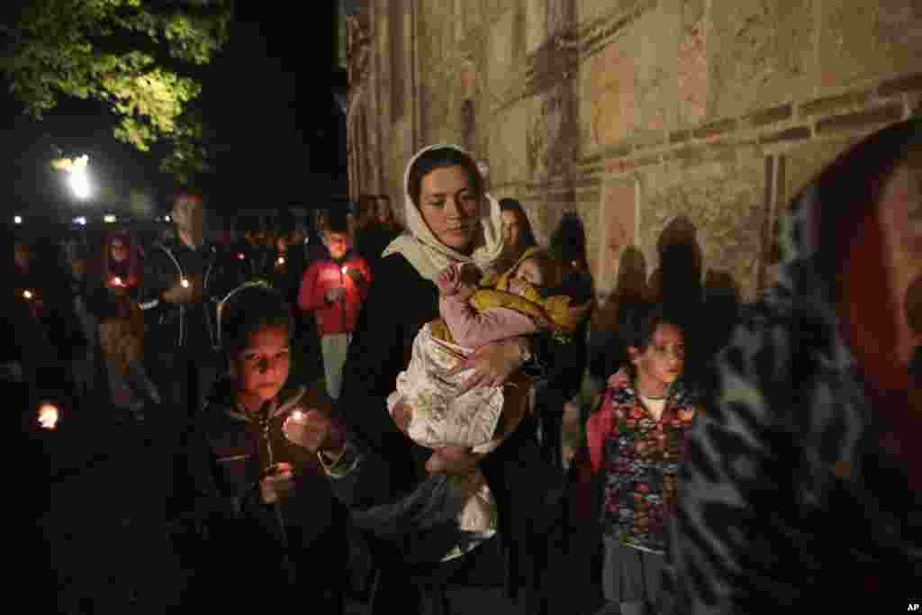 Kosovo Serb Orthodox woman holds her baby during an Easter vigil mass in the monastery of Gracanica during an Easter service, Kosovo, April 16, 2017. 