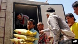 A Yemeni volunteer carries bags of rice to displaced people who fled fighting in the southern city of Aden, during a food distribution effort in Taiz, May 9, 2015.