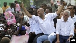 Haiti's presidential candidate Michel Martelly, center, accompanied by fellow candidate Charles-Henri Baker, right, and musician Wyclef Jean ride atop a vehicle through Port-au-Prince to demonstrate against the general elections in Haiti, Sunday, Nov. 28,