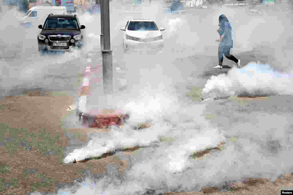 A Palestinian photographer runs away from tear gas fired by Israeli forces during a protest against Bahrain&#39;s workshop for U.S. peace plan, near the Jewish settlement of Beit El, in the Israeli-occupied West Bank, June 25, 2019.