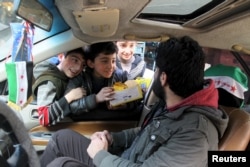 Boys try to sell biscuits to a man driving a car in Aleppo, Syria, March 2, 2016.