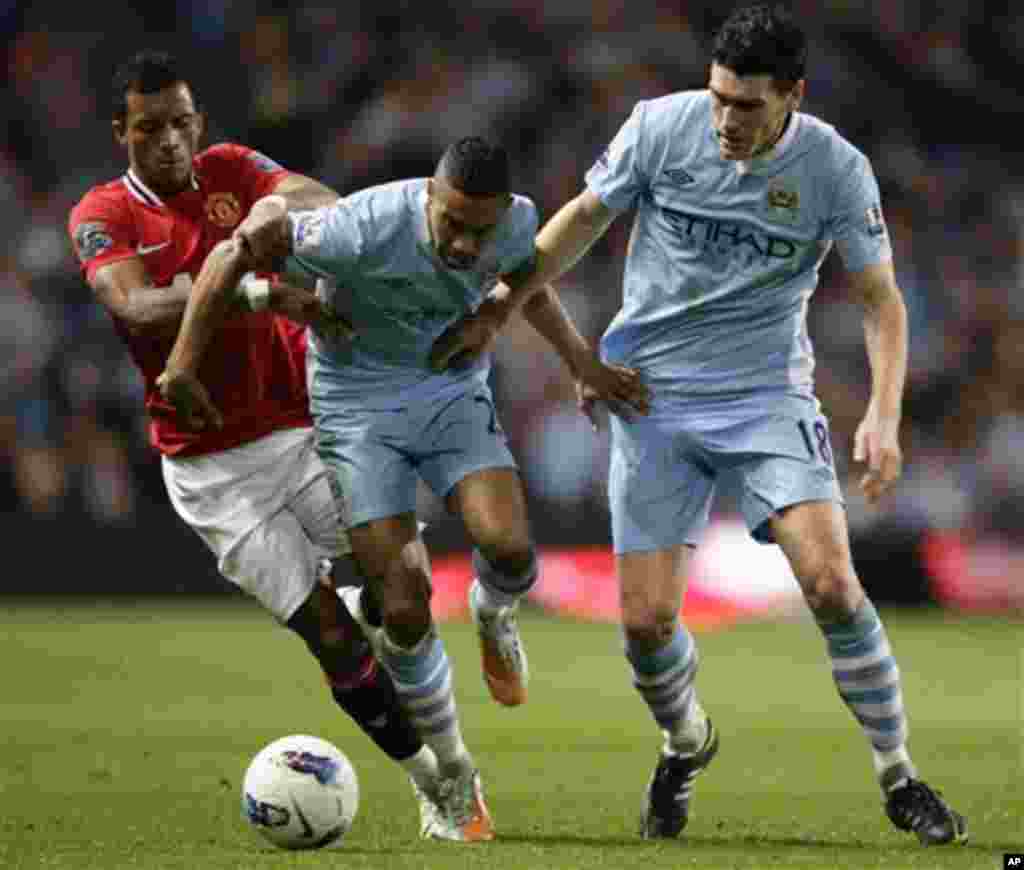 Manchester City's Gael Clichy, centre, and Gareth Barry keep the ball from Manchester United's Nani during their English Premier League soccer match at The Etihad Stadium, Manchester, England, Monday, April 30, 2012. (AP Photo/Jon Super)