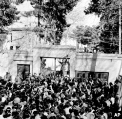 FILE- An army officer rallies a crowd of supporters of Shah Mohammed Reza Pahlevi in front of the home of Iranian Prime Minister Mohammed Mossadegh as riots broke out in Tehran, Feb. 28, 1953.