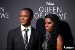 FILE - Robert Katende (L) and Ugandan chess player Phiona Mutesi (R), who are portrayed in "Queen of Katwe," pose at the film's Los Angeles premiere in Hollywood, California, Sept. 20, 2016.