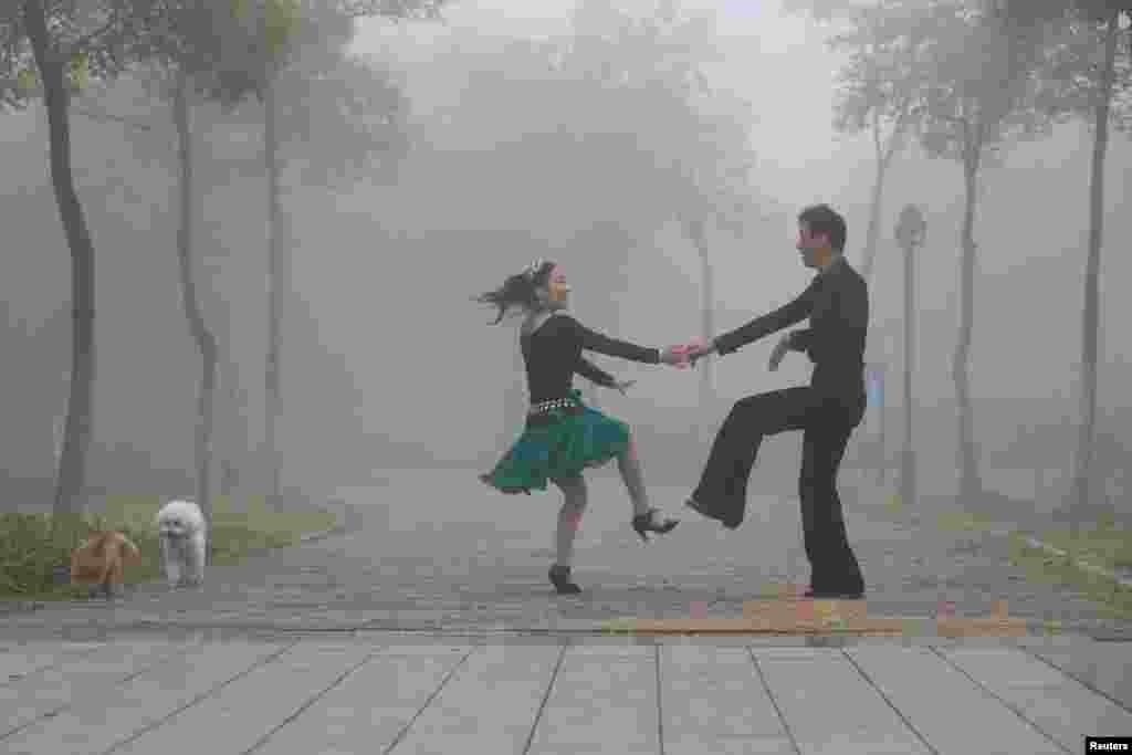 中国江苏淮安，浓雾中男女起舞，旁边有两只小狗（2017年10月10日）。