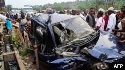 Orang-orang mengamati mobil yang rusak akibat kecelakaan lalu lintas di Mong-Ngafula distrik, di Kinshasa, Republik Demokratik Kongo, 16 Februari 2020. (Foto: Junior KANNAH / AFP)