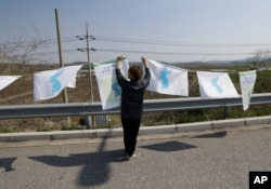 A man hangs unification flags near Unification Bridge, which leads to the Panmunjom in Paju, South Korea, April 25, 2018. South Korean President Moon Jae-in and North Korean leader Kim Jong Un will meet at the southern side of the Panmunjom, April 27.