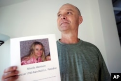 FILE - Bill Engfelt holds the flyer he made while searching for information on his sister, Mirella Harrison, in Solana Beach, Calif., Nov. 27, 2018.