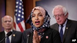 ຜູ້​ແທນ​ສະ​ພາ​ຕ່ຳ Ilhan Omar, ສັງ​ກັດ​ພັກ​ດີ​ໂມ​ແຄ​ຣັດ​ຈາກ​ລັດ ມິນ​ເນ​ໂຊ​ຕາ (ກາງ) ກ່າວ​ໃນ​ກອງ​ປະ​ຊຸມ​ຖະ​ແຫລງ​ຂ່າວ ຢູ່​ຕຶກ​ຫ້ອງ​ການ​ລັດ​ຖະ​ສະ​ພາ, ນະ​ຄອນ​ຫລວງວໍ​ຊິງ​ຕັນ, ວັນ​ທີ 10, 2019