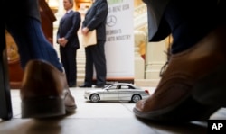 FILE- A Mercedes-Benz model sits in front of Robert Moran, director of communications for Mercedes-Benz USA, during a ceremony announcing the company's relocation of its U.S. corporate headquarters to the metro Atlanta city of Sandy Springs, Feb. 3, 2015.