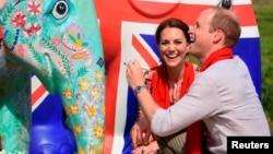 Britain's Prince William decorates an Elephant Parade statue as his wife Catherine, the Duchess of Cambridge, laughs during a visit to the Mark Shand Foundation at Kaziranga in the northeastern state of Assam, India, April 13, 2016.