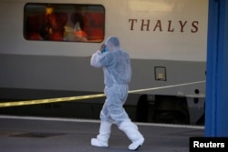 French investigating police in protective clothing prepare to enter the Thalys high-speed train where shots were fired to collect clues in Arras, France, Aug. 21, 2015.