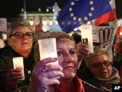 FILE - Poles protest plans by the ruling populist party for laws that would give it greater control over the courts and the national election commission, in Warsaw, Poland, Nov. 24, 2017. The evening demonstration came after lawmakers earlier in the day gave pre