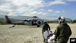 US Sailors assigned to Helicopter Sea Combat Squadron (HSC) 22 prepare to load an injured Haitian man onto an MH-60S Sea Hawk helicopter in Grand Goave, Haiti, Jan. 25, 2010