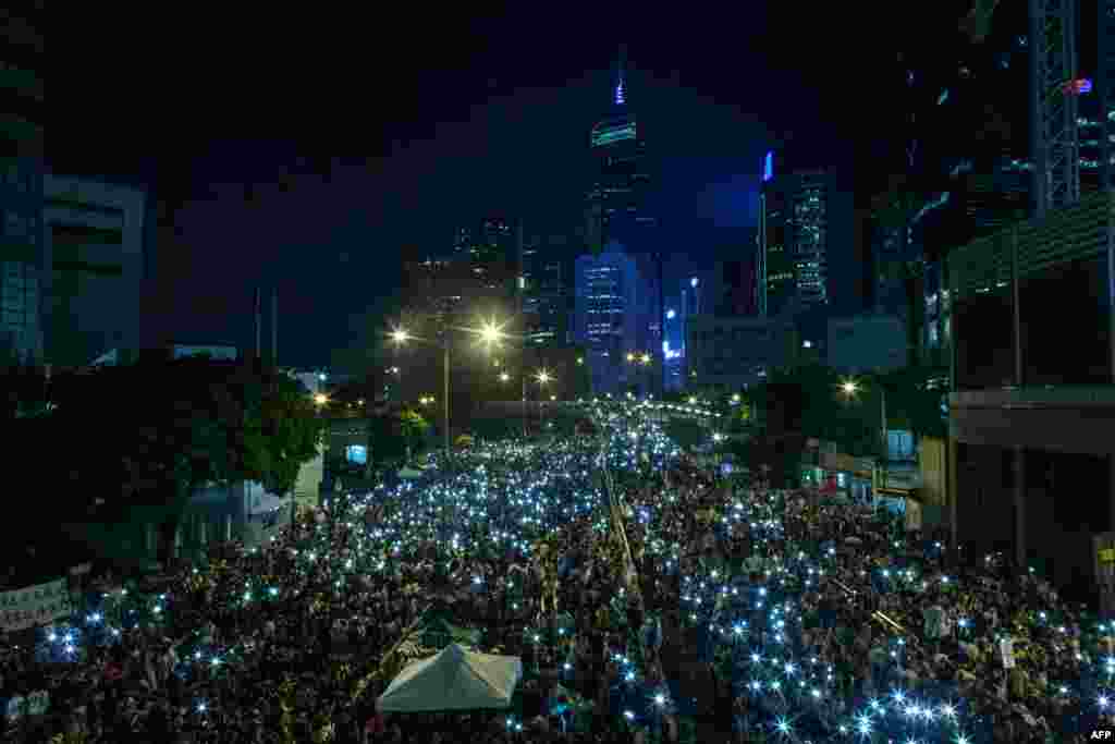 Pro-democracy protestors hold up their mobile phones after heavy rain in Hong Kong, Sept. 30, 2014. 
