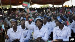 Women wave South Sudanese flags as they attend the country's anniversary celebrations, at the John Garang mausoleum in Juba, South Sudan, Monday, July 9, 2012.