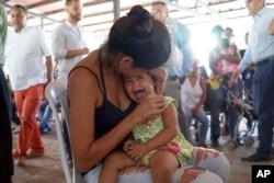 A Venezuelan woman holds a girl at a health post for migrants in Cucuta, along Colombia's border with Venezuela, July 16, 2018.