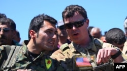 A file photo taken on April 25, 2017 shows a US officer from the US-led coalition, speaking with a fighter from the Kurdish People's Protection Units (YPG) at the site of Turkish airstrikes near northeastern Syrian Kurdish town of Derik.