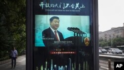 A man and vehicles pass by an electronic display panel advertising a video footage of Chinese President Xi Jinping on a street in Beijing, May 24, 2018. China and Japan have both condemned the Trump administration's decision to launch an investigation into whether tariffs are needed on imports of vehicles and automotive parts into the United States.