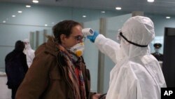 A passenger wearing a mask as a precaution against a new coronavirus has his temperature checked before boarding a flight to Vladivostok, Russia, at the Pyongyang International Airport in Pyongyang, North Korea, Monday, March 9, 2020. (AP Photo/Cha Song Ho)