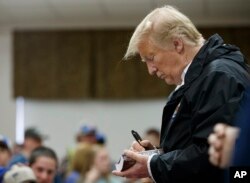 President Donald Trump signs a Bible as he greets people at Providence Baptist Church in Smiths Station, Ala., March 8, 2019, during a tour of areas where tornadoes killed 23 people in Lee County, Ala.